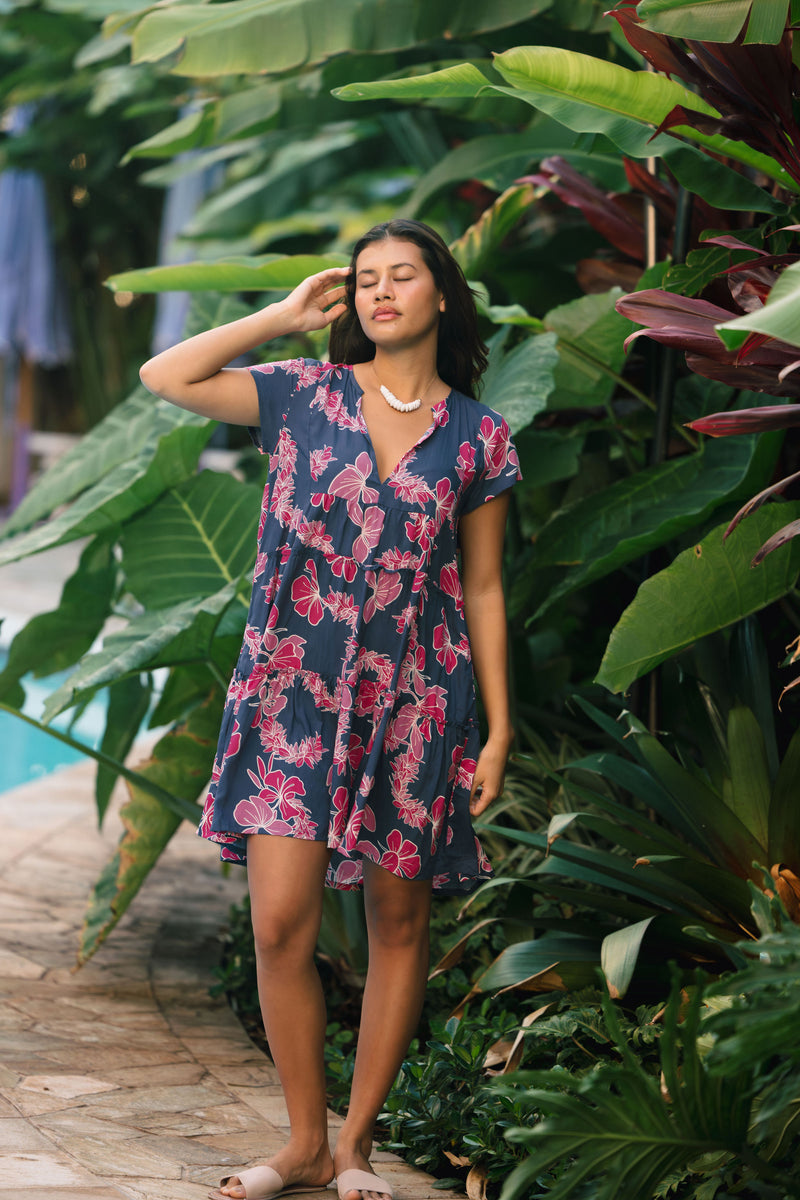 Woman wearing dress in navy with pink ginger and lei print.