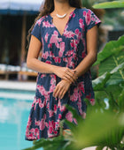 Woman wearing dress in navy with pink ginger and lei print.