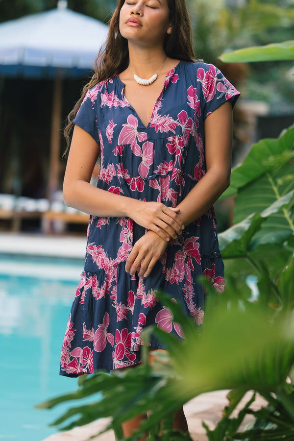 Woman wearing dress in navy with pink ginger and lei print.