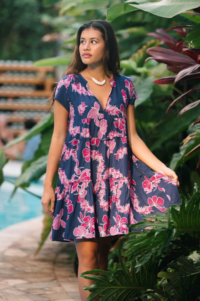 Woman wearing dress in navy with pink ginger and lei print.