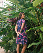 Woman wearing dress in navy with pink ginger and lei print.