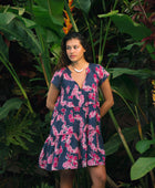 Woman wearing dress in navy with pink ginger and lei print.