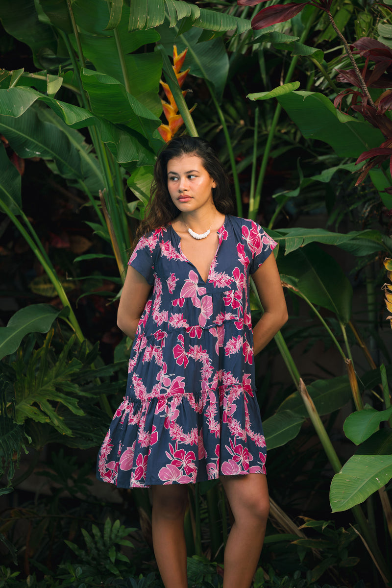 Woman wearing dress in navy with pink ginger and lei print.