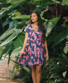 Woman wearing dress in navy with pink ginger and lei print.