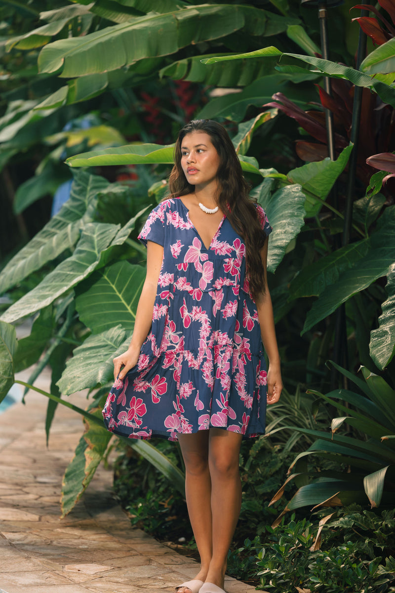 Woman wearing dress in navy with pink ginger and lei print.