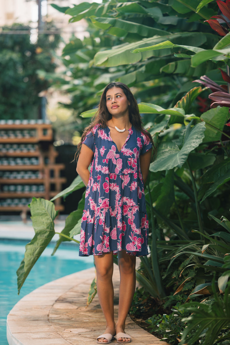 Woman wearing dress in navy with pink ginger and lei print.