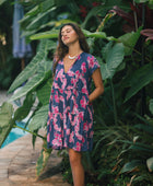 Woman wearing dress in navy with pink ginger and lei print.