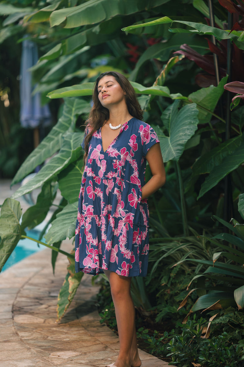 Woman wearing dress in navy with pink ginger and lei print.