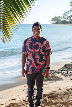 Man in button up shirt with dark navy ground and pink ginger and lei.
