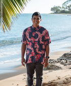 Man in button up shirt with dark navy ground and pink ginger and lei.