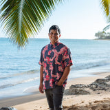 Man in button up shirt with dark navy ground and pink ginger and lei.