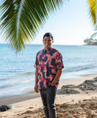 Man in button up shirt with dark navy ground and pink ginger and lei.