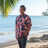 Man in button up shirt with dark navy ground and pink ginger and lei.