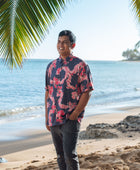 Man in button up shirt with dark navy ground and pink ginger and lei.