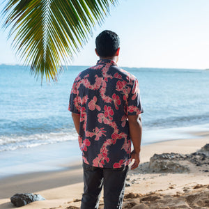 Man in button up shirt with dark navy ground and pink ginger and lei.