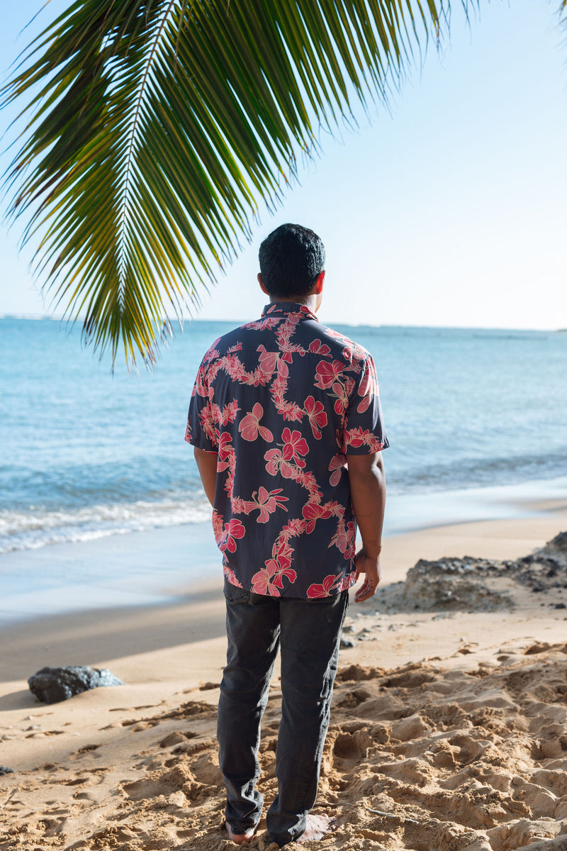 Man in button up shirt with dark navy ground and pink ginger and lei.