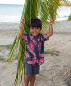 Boy in button up shirt with dark navy ground and pink ginger and lei.