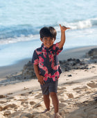 Boy in button up shirt with dark navy ground and pink ginger and lei.