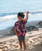 Boy in button up shirt with dark navy ground and pink ginger and lei.