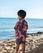 Boy in button up shirt with dark navy ground and pink ginger and lei.