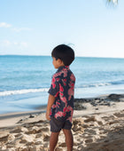 Boy in button up shirt with dark navy ground and pink ginger and lei.