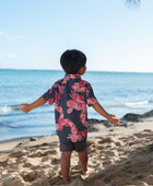 Boy in button up shirt with dark navy ground and pink ginger and lei.