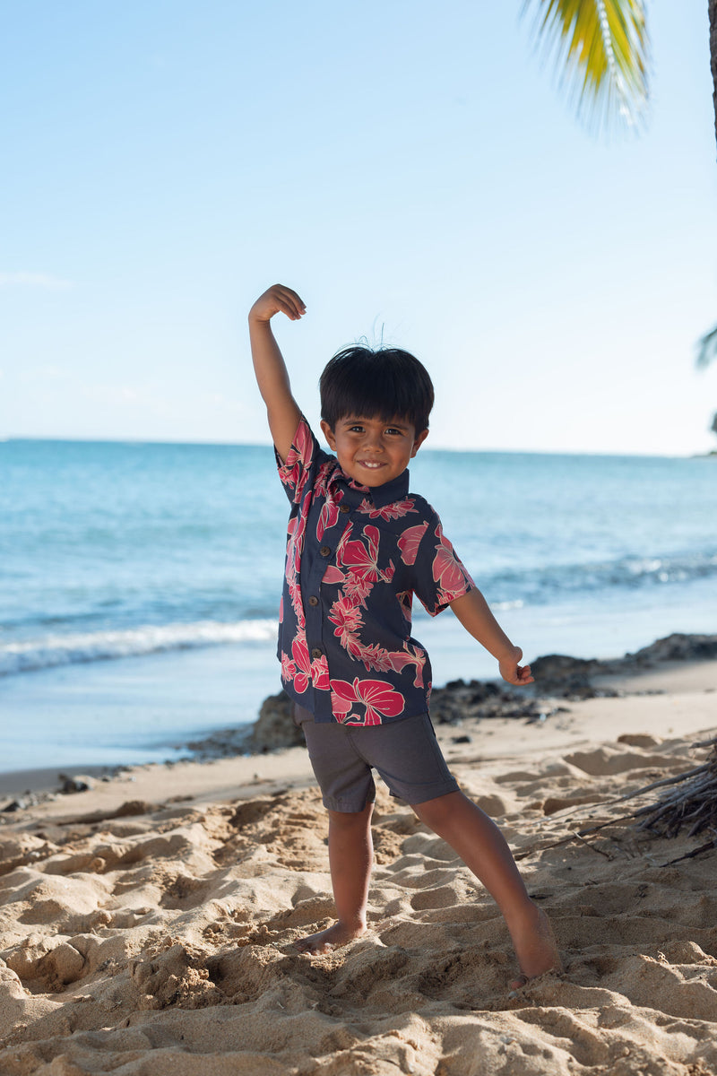 Boy in button up shirt with dark navy ground and pink ginger and lei.