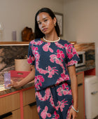 Woman wearing top and pants in navy with pink ginger and lei print.