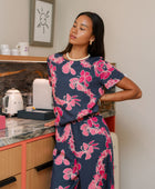 Woman wearing top and pants in navy with pink ginger and lei print.