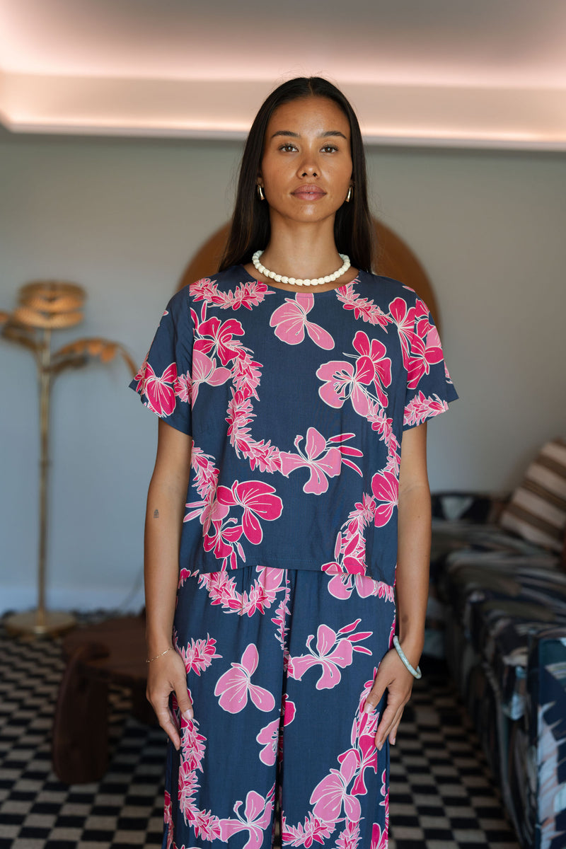 Woman wearing top and pants in navy with pink ginger and lei print.