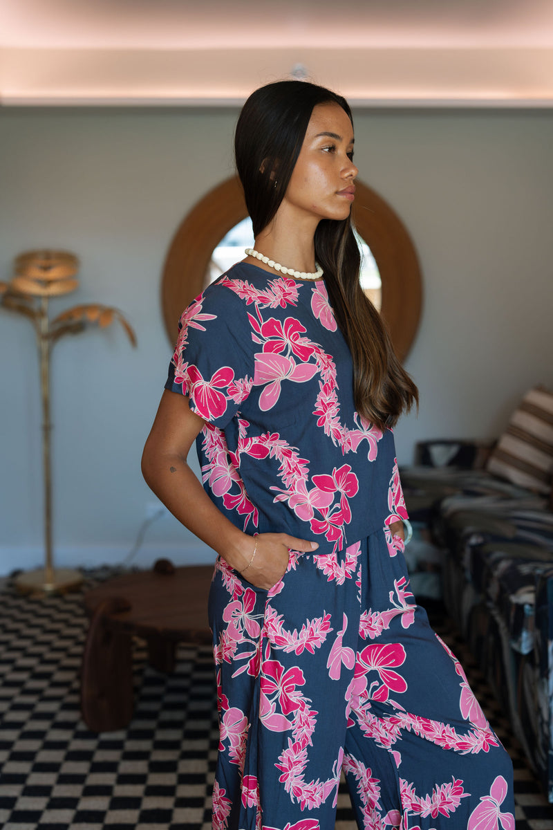 Woman wearing top and pants in navy with pink ginger and lei print.