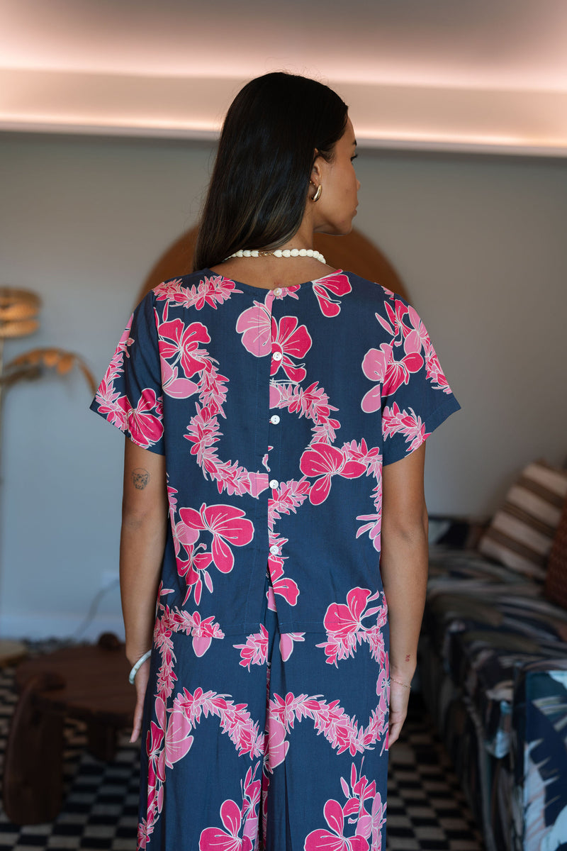 Woman wearing top and pants in navy with pink ginger and lei print.