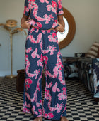 Woman with top and pants in navy with pink ginger and lei print.