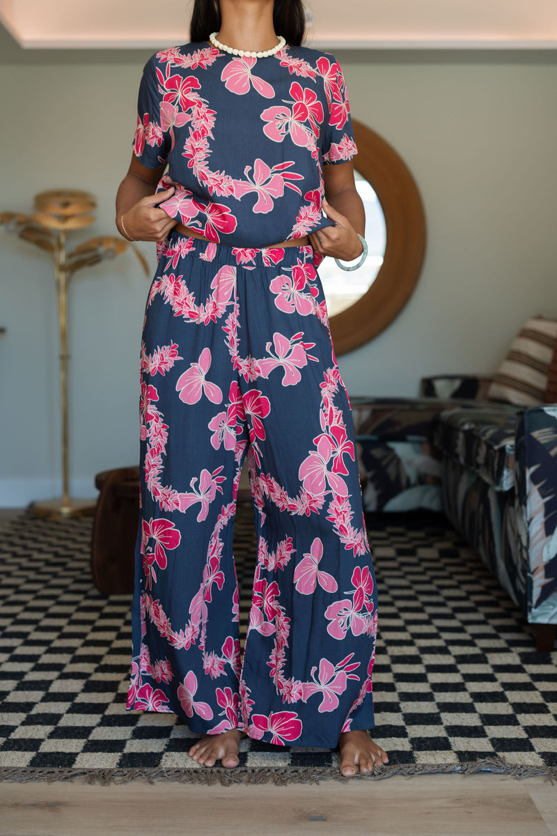 Woman with top and pants in navy with pink ginger and lei print.