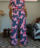 Woman with top and pants in navy with pink ginger and lei print.