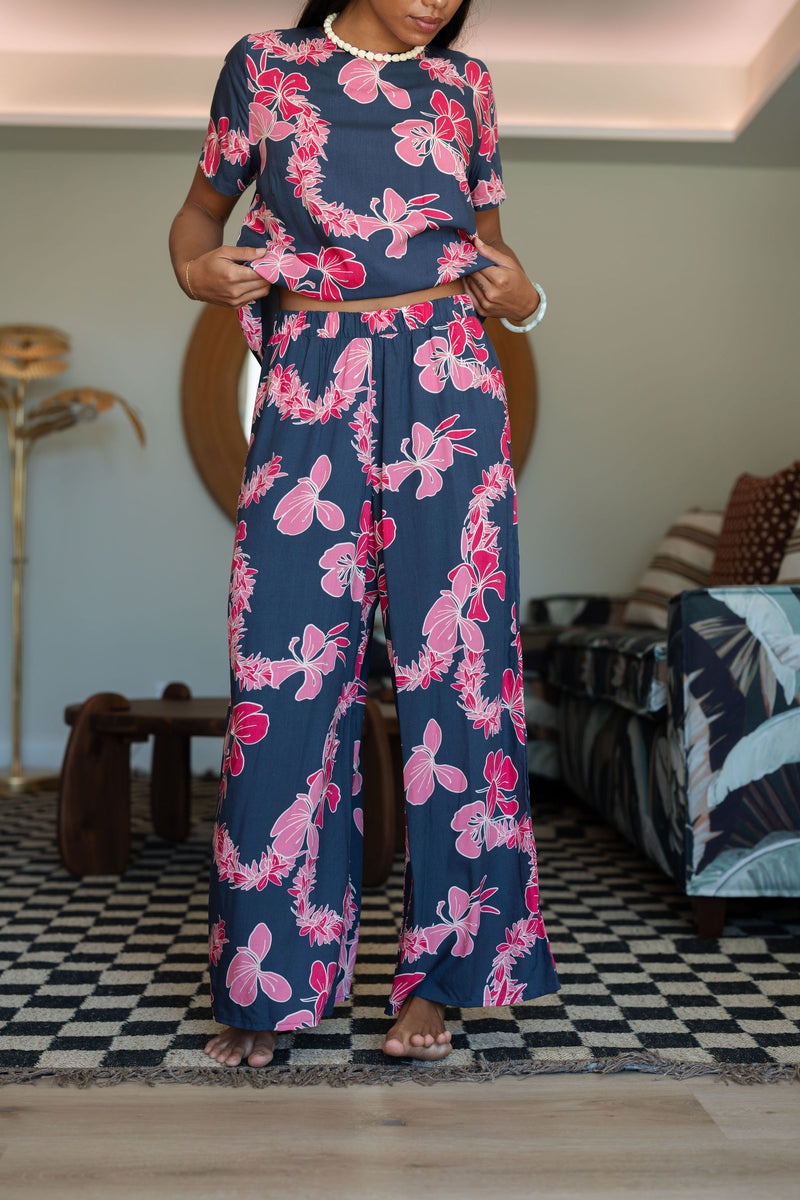 Woman with top and pants in navy with pink ginger and lei print.