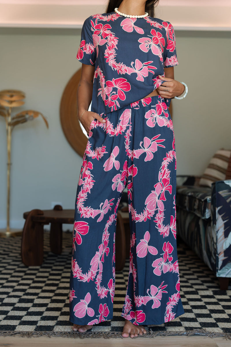 Woman with top and pants in navy with pink ginger and lei print.