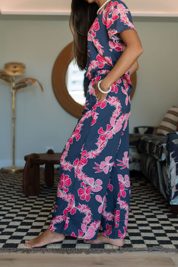 Woman with top and pants in navy with pink ginger and lei print.