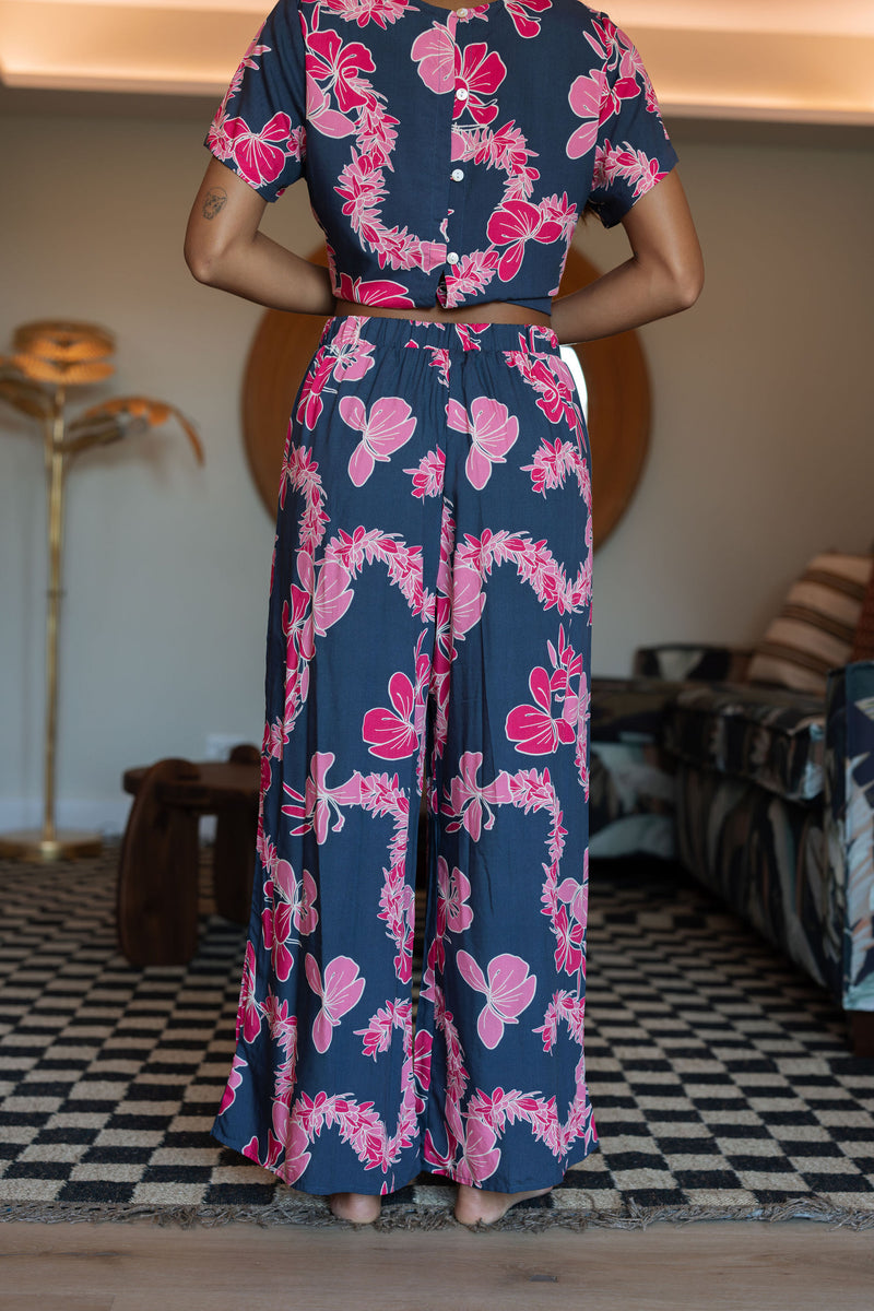 Woman with top and pants in navy with pink ginger and lei print.