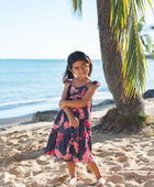 Girl in dress with dark navy ground and pink ginger and lei.