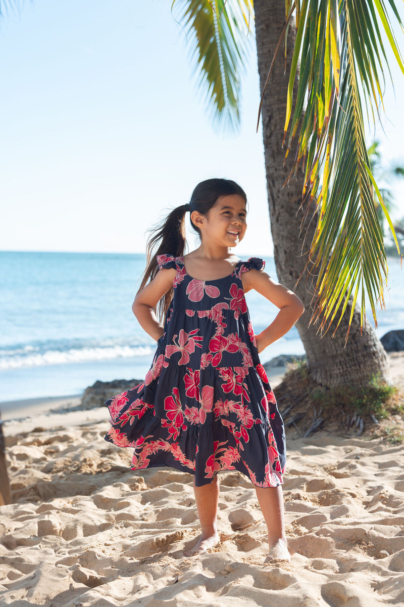 Girl in dress with dark navy ground and pink ginger and lei.