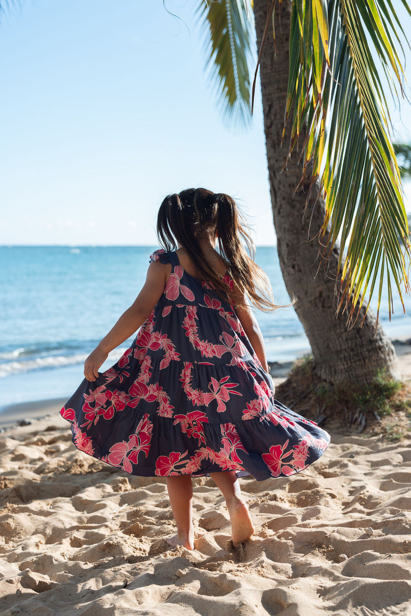 Girl in dress with dark navy ground and pink ginger and lei.