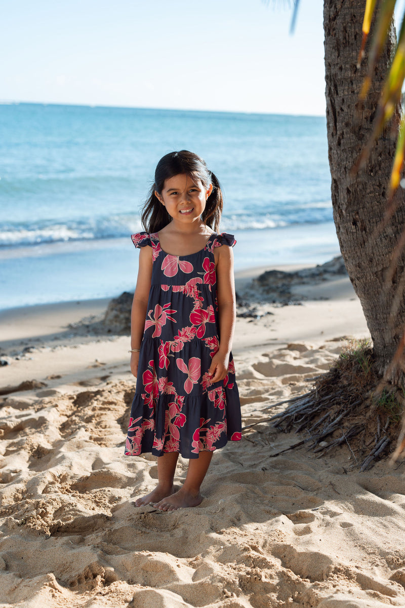 Girl in dress with dark navy ground and pink ginger and lei.