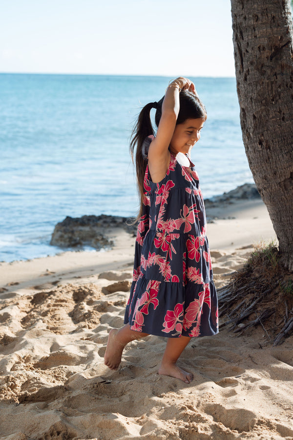 Girl in dress with dark navy ground and pink ginger and lei.