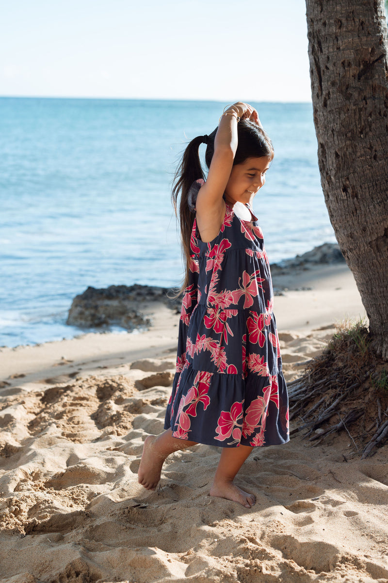 Girl in dress with dark navy ground and pink ginger and lei.