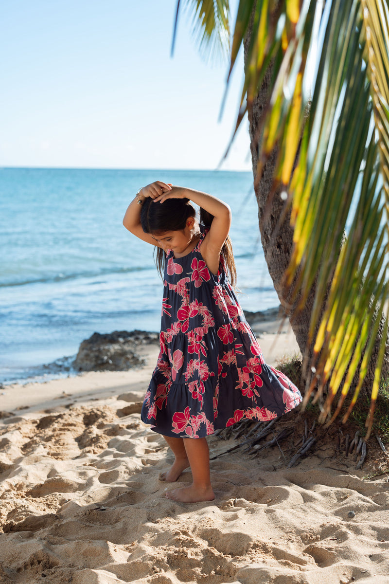 Girl in dress with dark navy ground and pink ginger and lei.