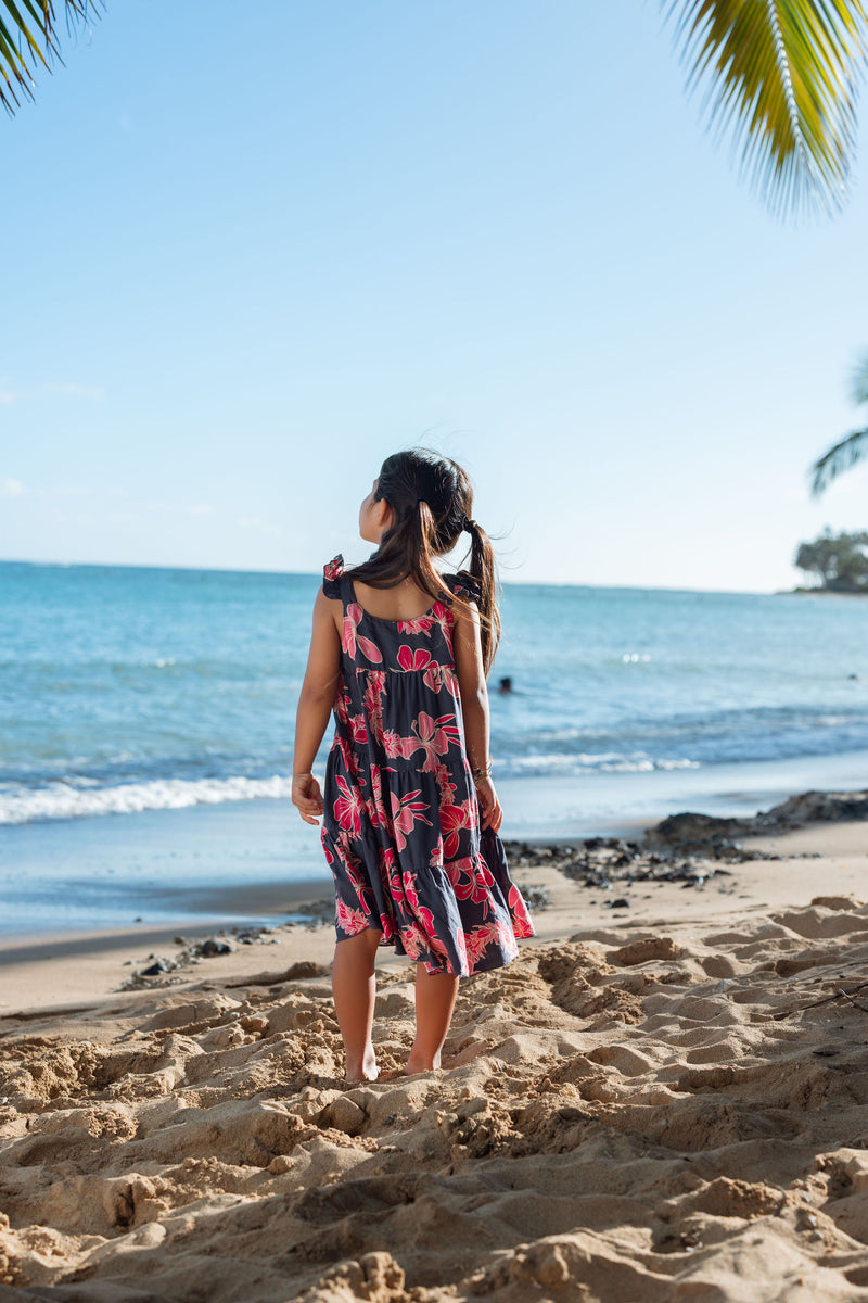 Girl in dress with dark navy ground and pink ginger and lei.