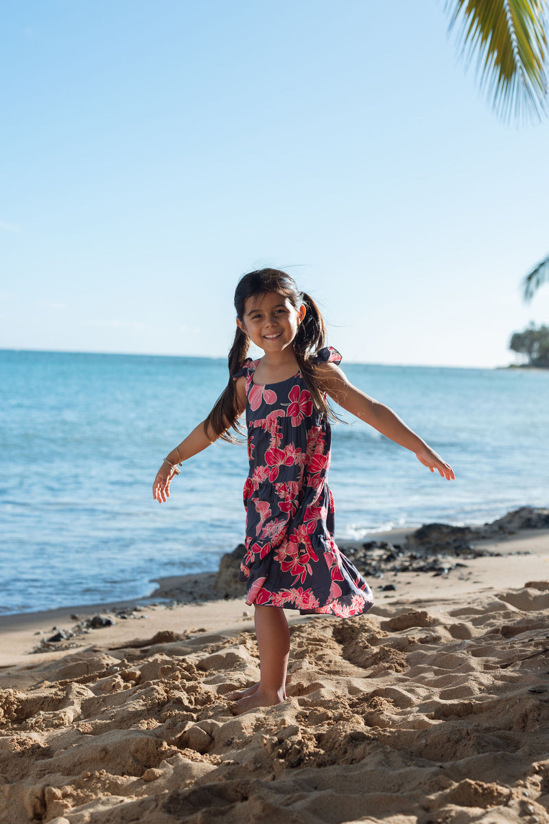 Girl in dress with dark navy ground and pink ginger and lei.