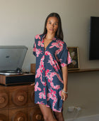 Woman in an above the knee shirt dress with dark navy ground and pink ginger and lei print.