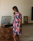 Woman in an above the knee shirt dress with dark navy ground and pink ginger and lei print.